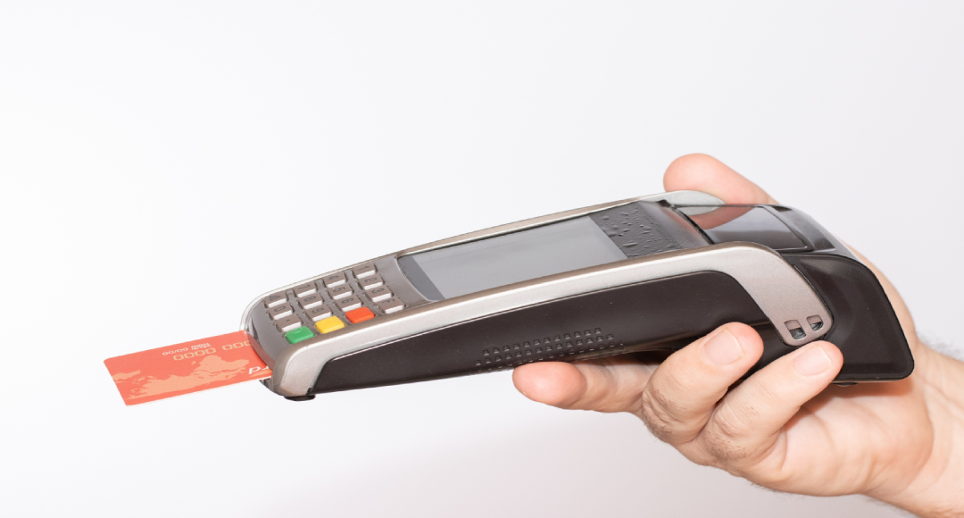 person-holding-payment-terminal-with-red-credit-card-swiped-through-machine
